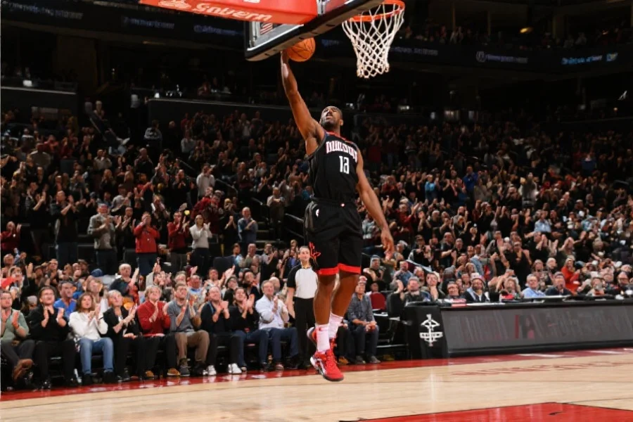 一位著名篮球运动员在赛场上灌篮，观众席上掌声雷动